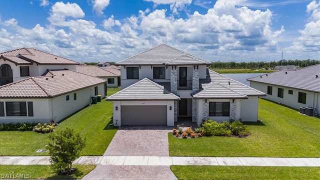 view of front of home with a garage, central AC, and a front lawn