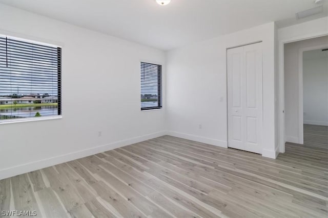 unfurnished bedroom with light hardwood / wood-style flooring and a closet