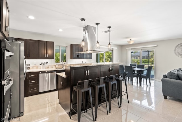 kitchen with pendant lighting, appliances with stainless steel finishes, a kitchen island, and plenty of natural light