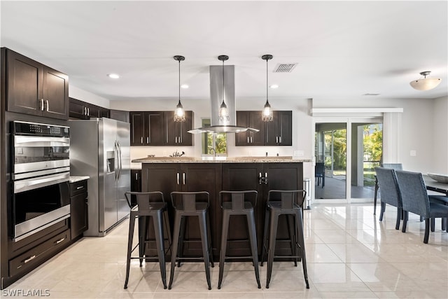 kitchen with hanging light fixtures, island range hood, light tile patterned floors, and stainless steel appliances