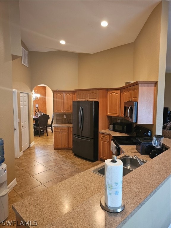 kitchen with tasteful backsplash, black appliances, kitchen peninsula, light tile patterned floors, and a high ceiling