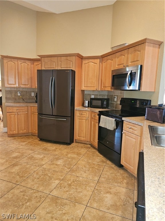 kitchen with light tile patterned flooring, black appliances, tasteful backsplash, a high ceiling, and sink