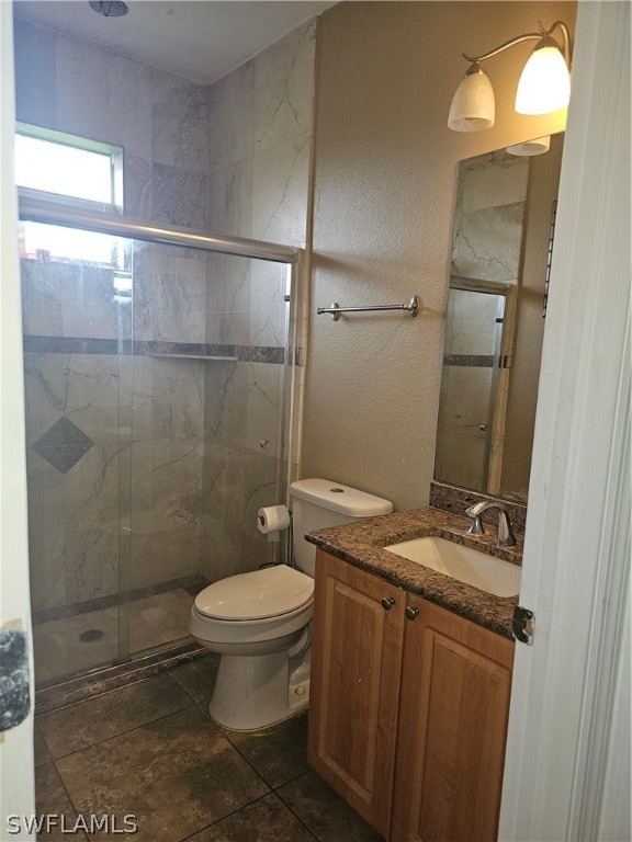 bathroom featuring vanity, a shower with door, tile patterned flooring, and toilet