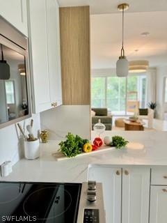 kitchen with white cabinetry, light stone counters, and decorative light fixtures