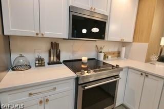 kitchen with tasteful backsplash, appliances with stainless steel finishes, and white cabinets