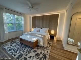 bedroom featuring dark hardwood / wood-style flooring, ceiling fan, and crown molding