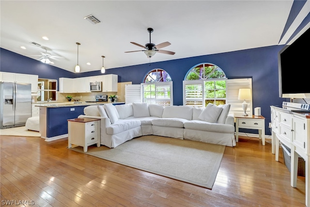 living room featuring lofted ceiling, light hardwood / wood-style floors, and ceiling fan