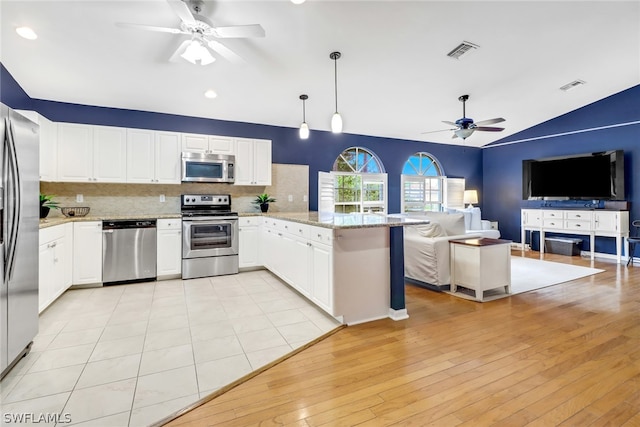 kitchen with appliances with stainless steel finishes, vaulted ceiling, decorative backsplash, and white cabinets