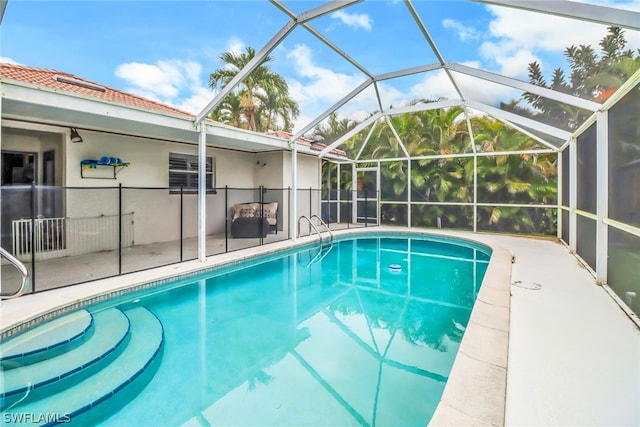 view of swimming pool featuring glass enclosure and a patio area