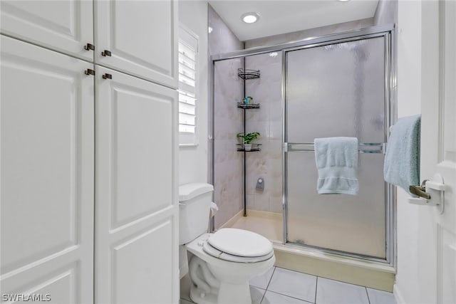 bathroom featuring tile patterned flooring, toilet, and walk in shower