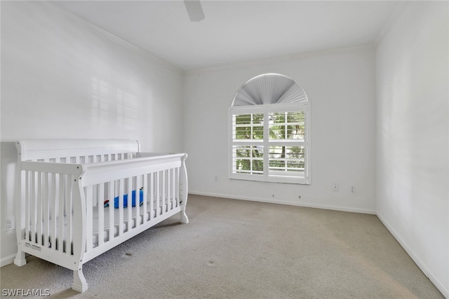 unfurnished bedroom featuring ceiling fan, ornamental molding, carpet, and a crib