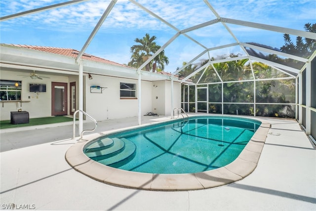 view of pool with ceiling fan, glass enclosure, and a patio area