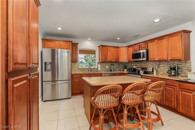 kitchen featuring sink, light tile patterned floors, appliances with stainless steel finishes, light stone countertops, and a kitchen island