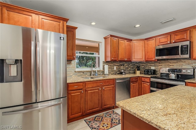 kitchen with sink, stainless steel appliances, light stone countertops, light tile patterned flooring, and decorative backsplash