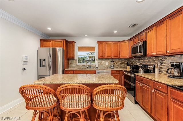 kitchen with light stone countertops, appliances with stainless steel finishes, a center island, and a breakfast bar area