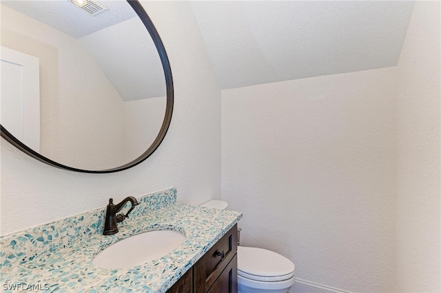 bathroom with vanity, lofted ceiling, toilet, and a textured ceiling