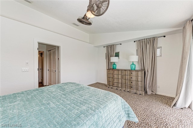 carpeted bedroom with a textured ceiling and vaulted ceiling