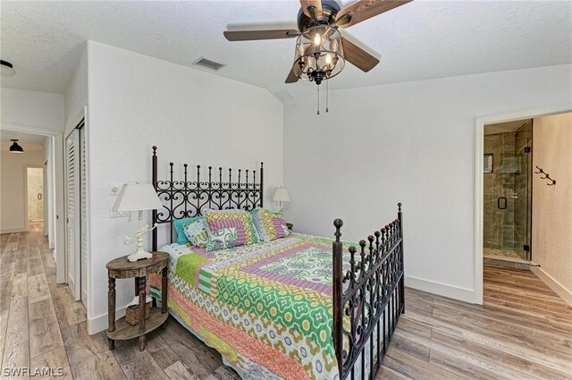 bedroom featuring ceiling fan, a textured ceiling, hardwood / wood-style flooring, a closet, and ensuite bath