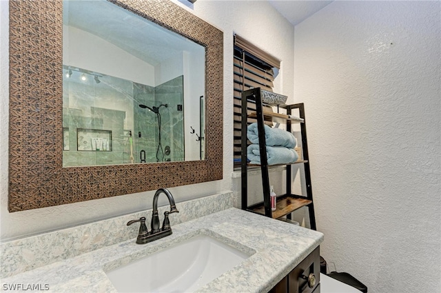 bathroom with a shower with door, vaulted ceiling, and vanity