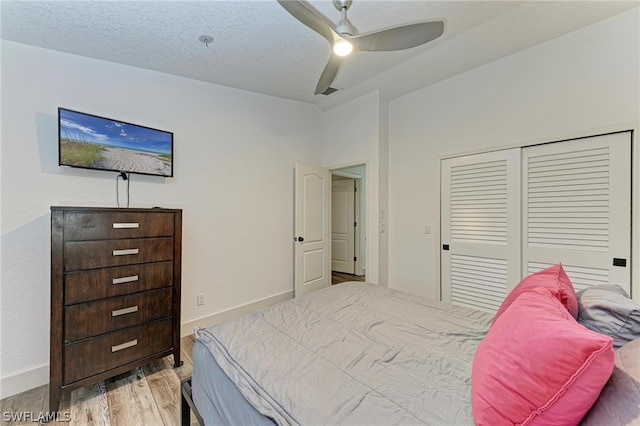 bedroom with ceiling fan, a textured ceiling, light hardwood / wood-style flooring, and a closet