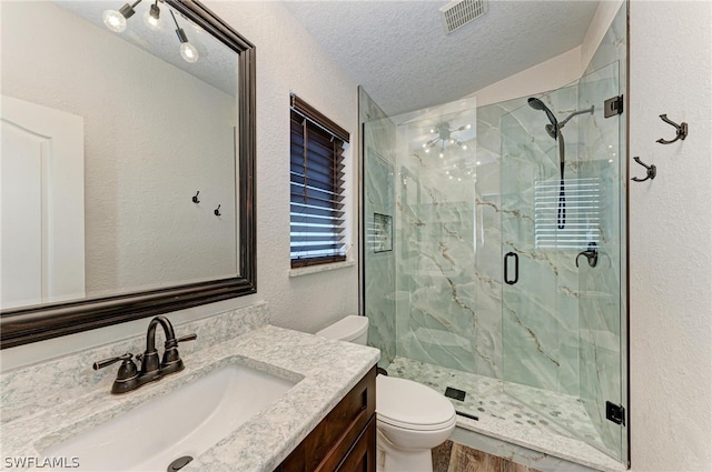 bathroom featuring vanity, a textured ceiling, hardwood / wood-style flooring, walk in shower, and toilet