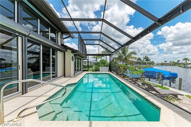 view of swimming pool featuring glass enclosure, a water view, and a patio area