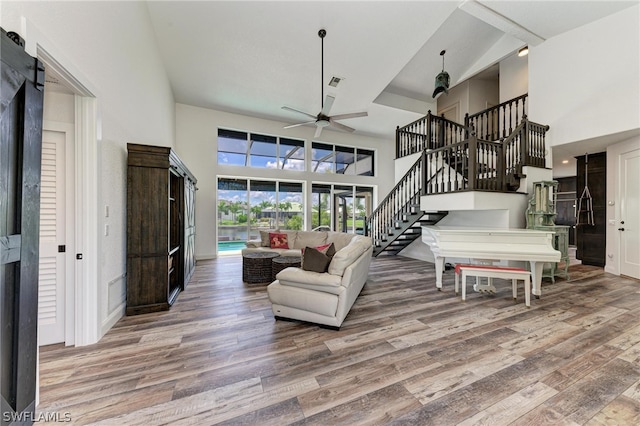 living room featuring a towering ceiling, ceiling fan, and hardwood / wood-style floors