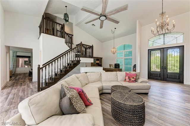 living room with ceiling fan with notable chandelier, high vaulted ceiling, hardwood / wood-style flooring, and french doors