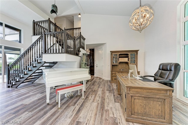 office space featuring an inviting chandelier, light hardwood / wood-style floors, high vaulted ceiling, and a healthy amount of sunlight