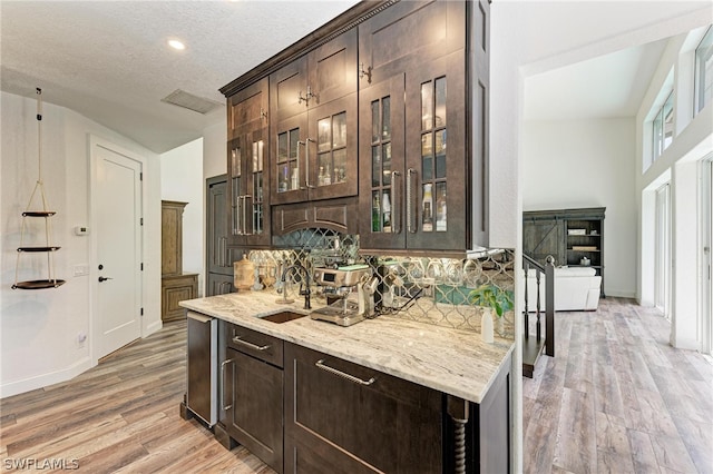 interior space with dark brown cabinets, a textured ceiling, light hardwood / wood-style flooring, and sink