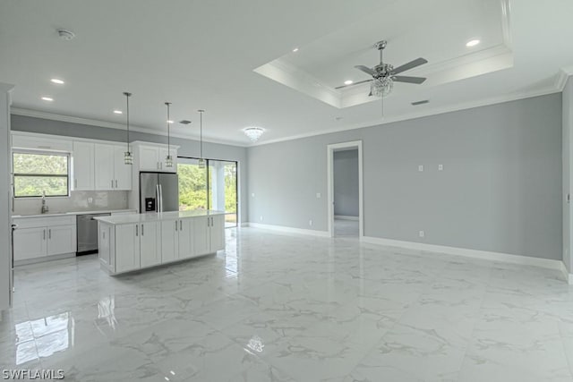 kitchen featuring a kitchen island, appliances with stainless steel finishes, pendant lighting, white cabinets, and a raised ceiling