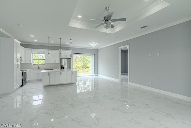 unfurnished living room featuring ceiling fan, ornamental molding, a tray ceiling, and sink