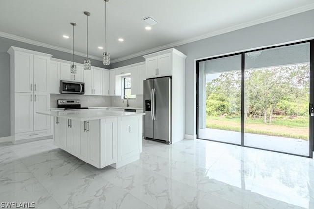 kitchen with a center island, white cabinets, crown molding, appliances with stainless steel finishes, and decorative light fixtures