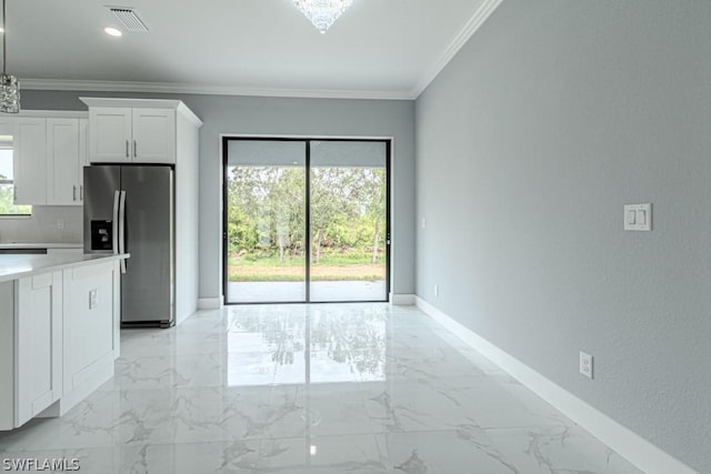 kitchen with ornamental molding, stainless steel fridge, and white cabinets