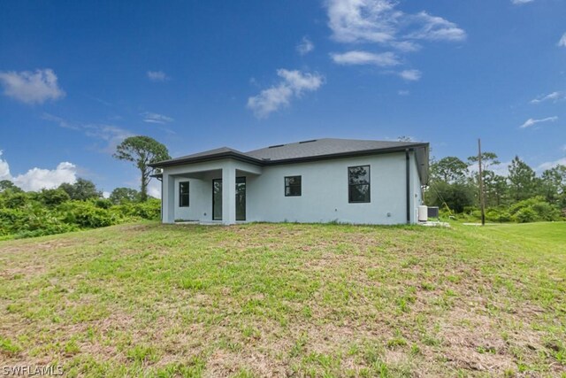 rear view of house featuring cooling unit and a lawn