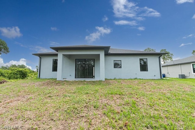 rear view of house featuring central AC and a lawn