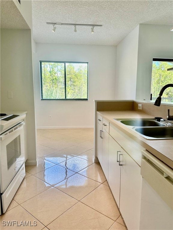 kitchen with white appliances, light tile patterned floors, a textured ceiling, and sink