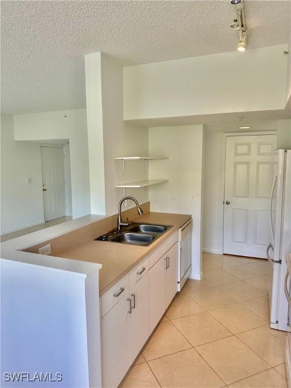 kitchen featuring white appliances, open shelves, light tile patterned flooring, a sink, and white cabinetry