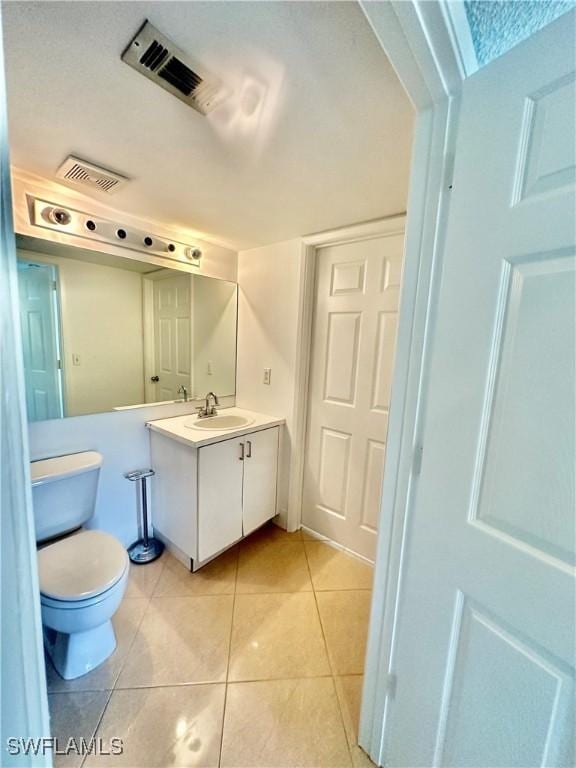 bathroom with tile patterned flooring, visible vents, toilet, and vanity