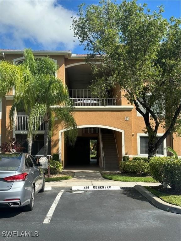 view of property featuring stairway and uncovered parking