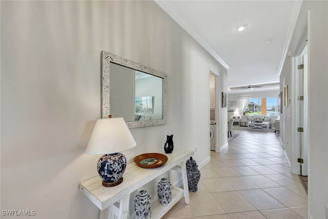 hallway featuring washer / clothes dryer, light tile patterned floors, and ornamental molding