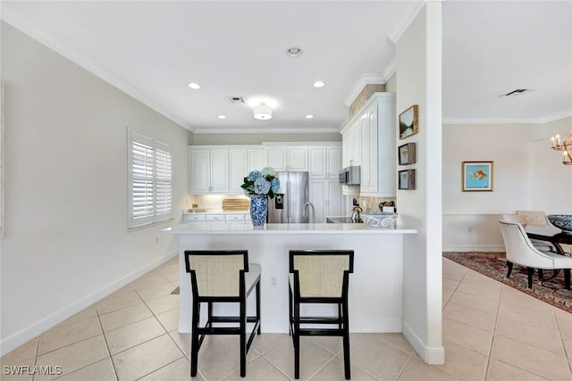 kitchen featuring stainless steel appliances, kitchen peninsula, crown molding, a breakfast bar, and white cabinets