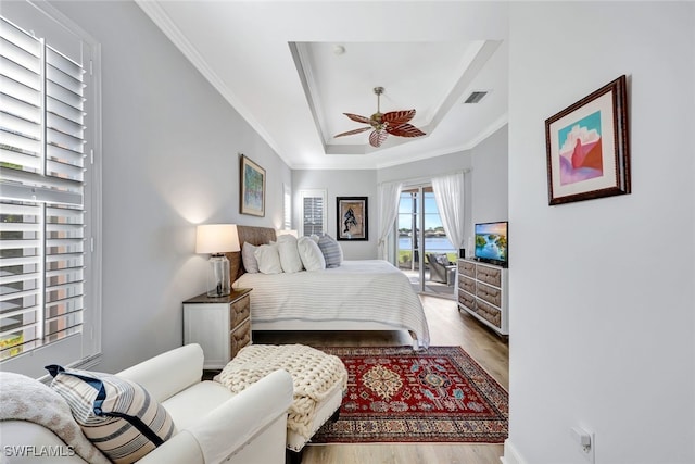 bedroom featuring ceiling fan, light hardwood / wood-style floors, a raised ceiling, and ornamental molding