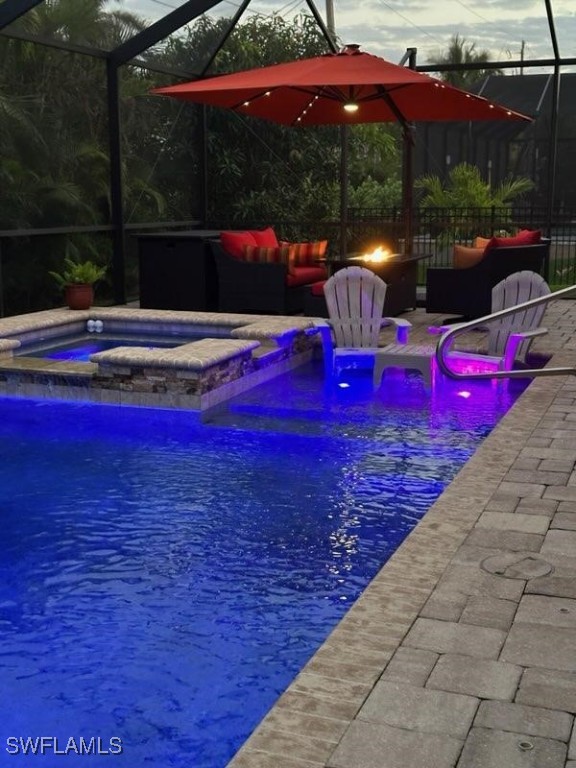 pool featuring glass enclosure, an in ground hot tub, and a patio