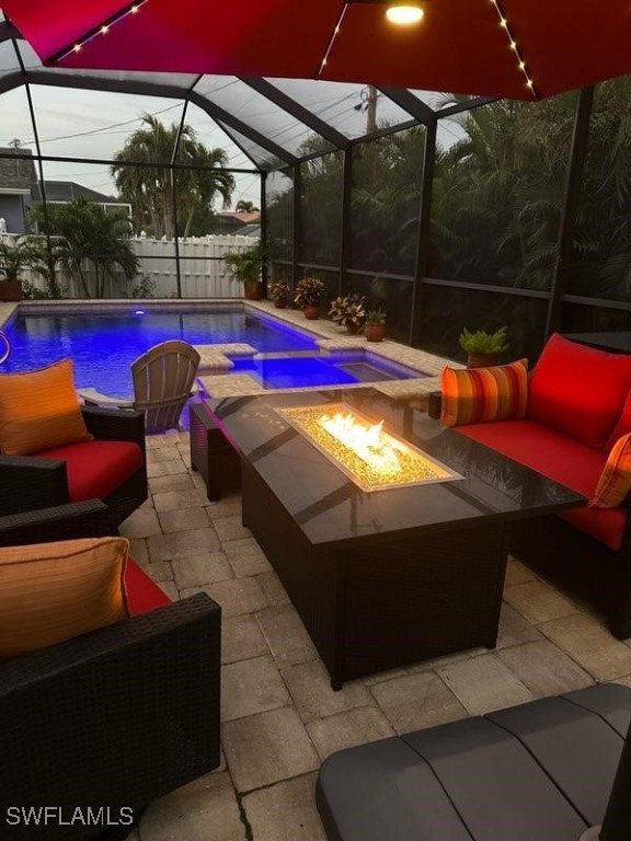 pool at dusk with glass enclosure, a patio area, and an outdoor living space with a fire pit