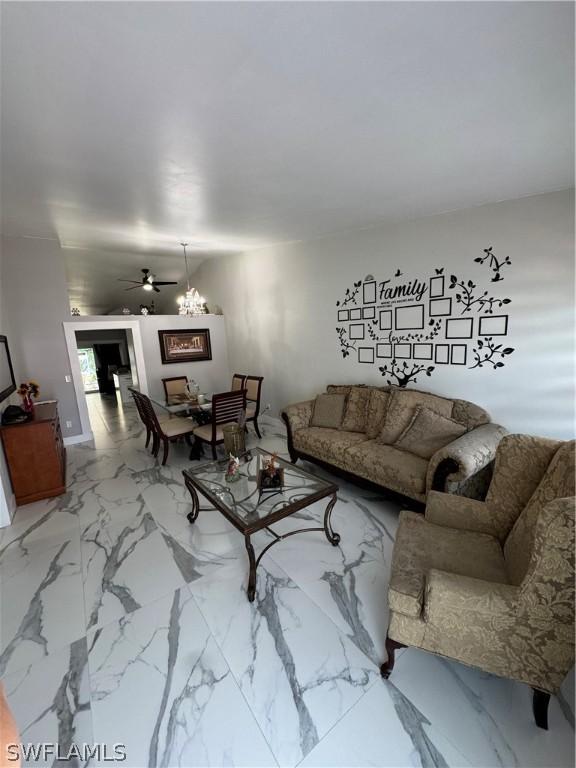 living room featuring ceiling fan with notable chandelier and tile patterned floors