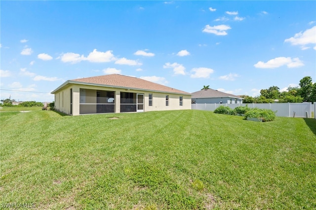 back of property featuring a sunroom and a lawn