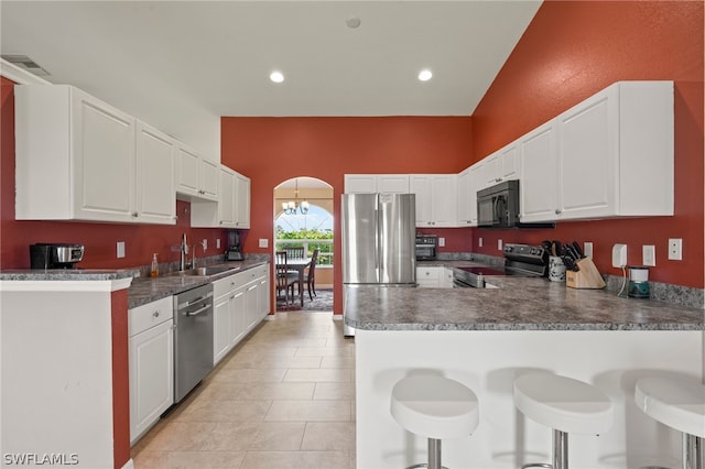 kitchen with kitchen peninsula, sink, white cabinetry, a breakfast bar area, and stainless steel appliances