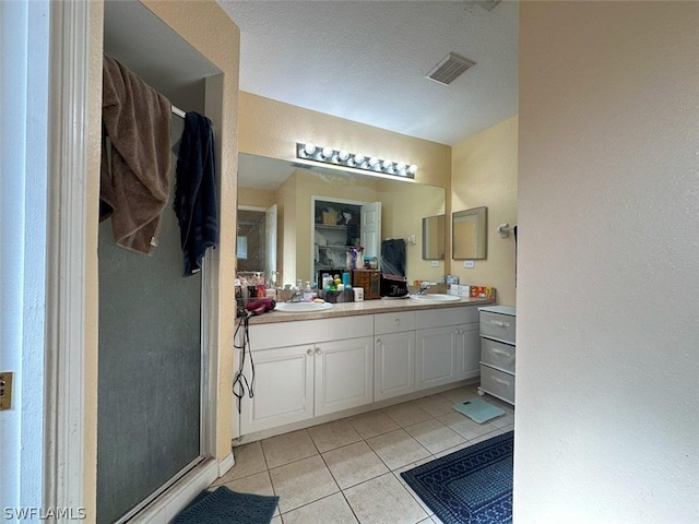 bathroom featuring dual vanity, a textured ceiling, and tile patterned flooring