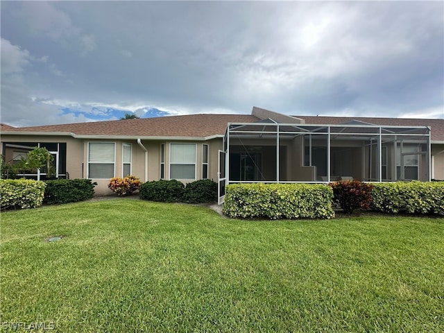 rear view of property with a lawn and glass enclosure